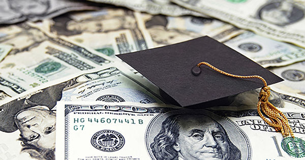 Mortar board with gold tassel atop a pile of money.