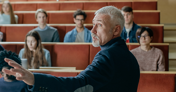 Professor teach in a lecture hall to several students.