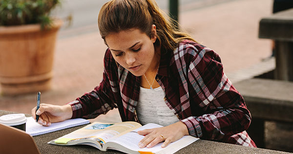 Female college student reading textbook.