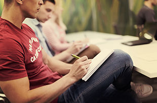 Male college student in class taking notes.